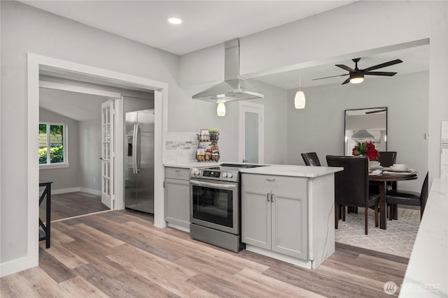 1106 Starling St, Steilacoom, WA 98388 - kitchen with stainless steel appliances, island range hood, light wood finished floors, a peninsula, and light countertops