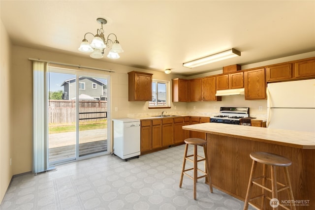 2376 Nicholas Dr, Ferndale, WA 98248 - kitchen with white appliances, under cabinet range hood, light countertops, a chandelier, and a breakfast bar area