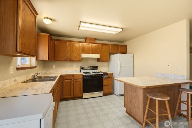 2376 Nicholas Dr, Ferndale, WA 98248 - kitchen featuring white appliances, under cabinet range hood, a peninsula, a kitchen bar, and brown cabinets