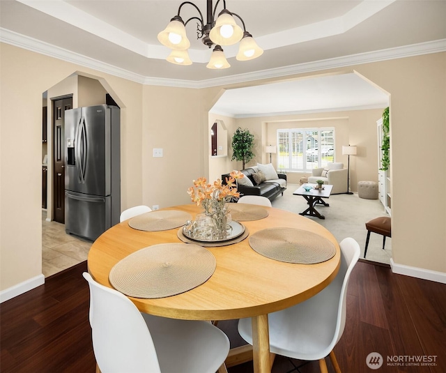 600 213th St SW, Bothell, WA 98021 - dining space featuring a chandelier, a raised ceiling, arched walkways, wood finished floors, and crown molding