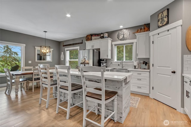 17501 Clearlake Blvd SE, Yelm, WA 98597 - kitchen with freestanding refrigerator, light countertops, white cabinetry, decorative backsplash, and a breakfast bar area