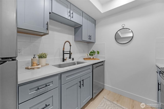 14600 NE 32nd St Unit I4, Bellevue, WA 98007 - kitchen featuring stainless steel appliances, gray cabinetry, tasteful backsplash, and light wood-style flooring
