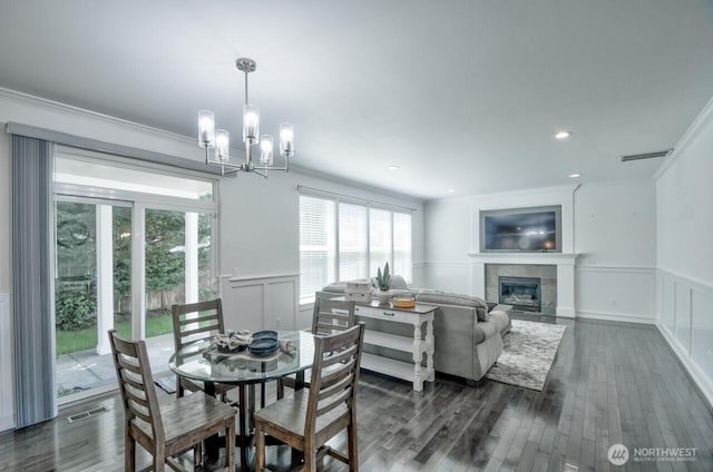 4704 204th Ct E, Spanaway, WA 98387 - dining space featuring a wainscoted wall, a chandelier, a tile fireplace, dark wood finished floors, and crown molding