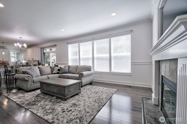 4704 204th Ct E, Spanaway, WA 98387 - living room featuring ornamental molding, a chandelier, dark wood-style flooring, a high end fireplace, and a wainscoted wall