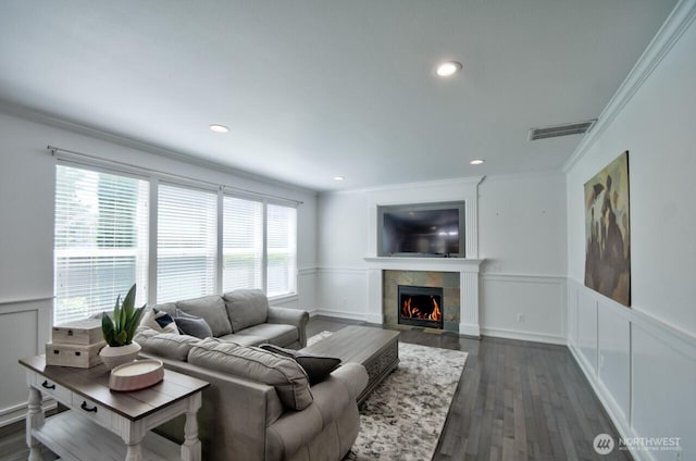4704 204th Ct E, Spanaway, WA 98387 - living area with a wainscoted wall, a tiled fireplace, crown molding, a decorative wall, and dark wood-style floors