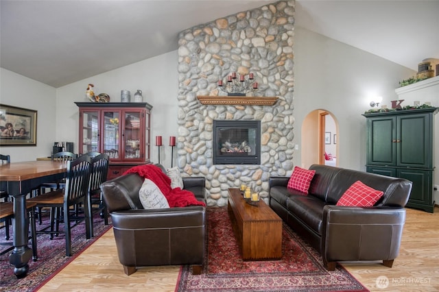 108 Garden Pl, Elma, WA 98541 - living room featuring vaulted ceiling, light wood-style floors, a stone fireplace, and arched walkways