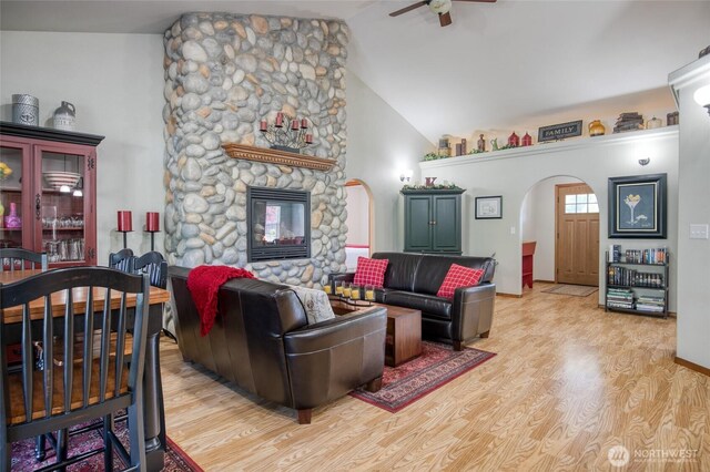 108 Garden Pl, Elma, WA 98541 - living room featuring a ceiling fan, lofted ceiling, light wood-style floors, arched walkways, and a stone fireplace