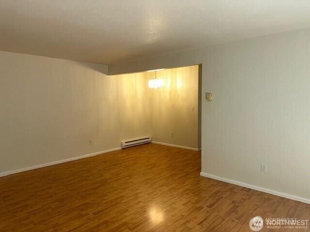 5722 122nd Pl SE Unit 235, Bellevue, WA 98006 - empty room featuring a baseboard heating unit, wood finished floors, and baseboards