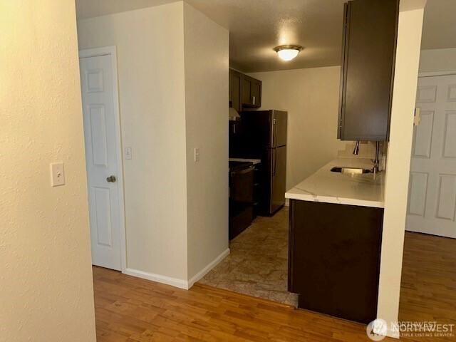 5722 122nd Pl SE Unit 235, Bellevue, WA 98006 - kitchen featuring a sink, light countertops, light wood-style floors, freestanding refrigerator, and baseboards
