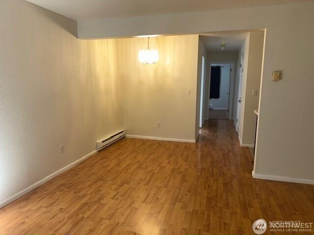 5722 122nd Pl SE Unit 235, Bellevue, WA 98006 - spare room featuring baseboard heating, wood finished floors, and baseboards