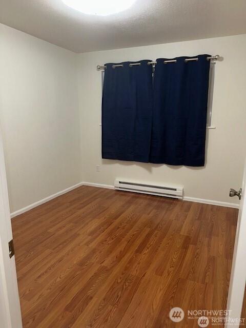 5722 122nd Pl SE Unit 235, Bellevue, WA 98006 - empty room featuring a baseboard radiator, wood finished floors, and baseboards
