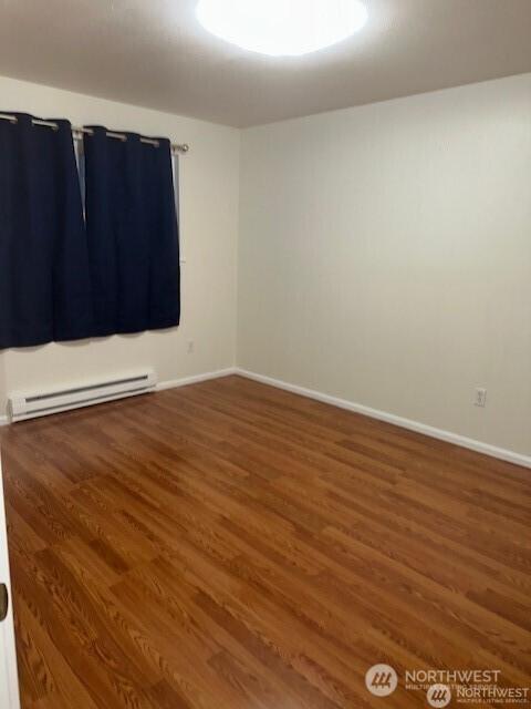 5722 122nd Pl SE Unit 235, Bellevue, WA 98006 - empty room featuring wood finished floors, a baseboard heating unit, and baseboards