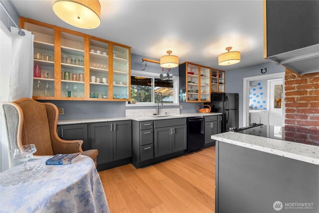 111 Norfolk Rd, Winthrop, WA 98862 - kitchen with separate washer and dryer, black appliances, light wood finished floors, glass insert cabinets, and light stone counters