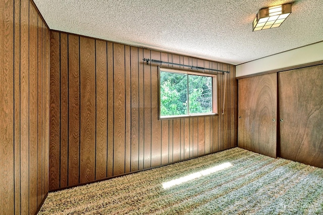 2781 Lake Whatcom Blvd, Bellingham, WA 98229 - unfurnished bedroom featuring a textured ceiling, carpet flooring, wood walls, and a closet