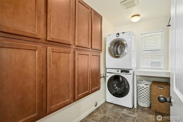 4915 NE 5th St, Renton, WA 98059 - laundry area featuring estacked washer and dryer, cabinet space, baseboards, and stone finish flooring