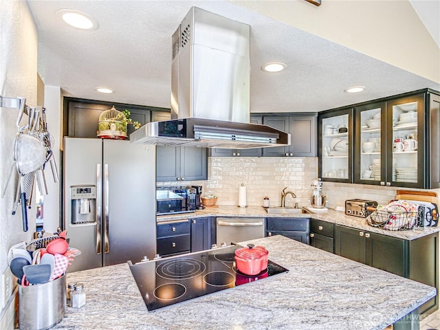 4425 65th St E, Tacoma, WA 98443 - kitchen with appliances with stainless steel finishes, island exhaust hood, decorative backsplash, a textured ceiling, and glass insert cabinets