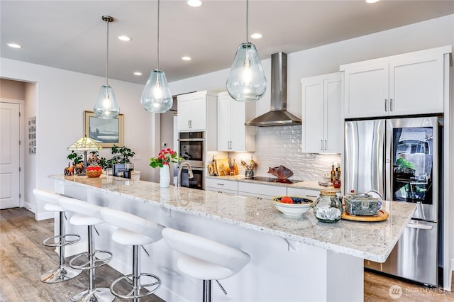 4689 Petrel St, Port Townsend, WA 98368 - kitchen featuring wall chimney exhaust hood, appliances with stainless steel finishes, white cabinets, light wood-style flooring, and a kitchen bar