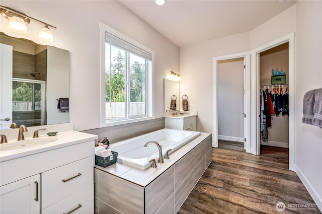 4689 Petrel St, Port Townsend, WA 98368 - bathroom featuring a stall shower, two vanities, wood finished floors, a bath, and a walk in closet