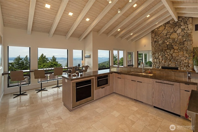 2000 Mount Dallas Rd, Friday Harbor, WA 98250 - kitchen with light brown cabinets, stone tile floors, open floor plan, a wood ceiling with exposed beams, and high vaulted ceiling