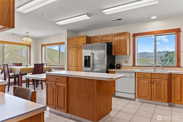 427 Rendezvous Rd, Winthrop, WA 98862 - kitchen with stainless steel fridge with ice dispenser, white dishwasher, light tile patterned floors, light countertops, and brown cabinets