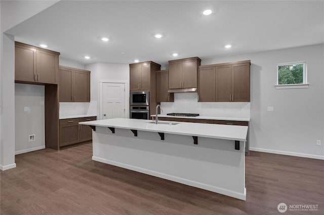 2605 S 7th Way, Ridgefield, WA 98642 - kitchen featuring appliances with stainless steel finishes, a sink, decorative backsplash, an island with sink, and dark wood-type flooring