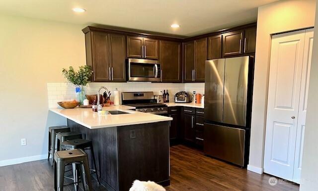 1342 Cascade St, Sultan, WA 98294 - kitchen with appliances with stainless steel finishes, a peninsula, a kitchen bar, a sink, and dark brown cabinetry