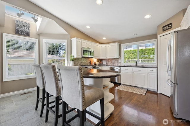 1910 Lenox Ct NW, Olympia, WA 98502 - kitchen featuring appliances with stainless steel finishes, dark countertops, white cabinetry, tasteful backsplash, and a breakfast bar area