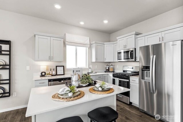 1725 Noble Ave Unit 81, Snohomish, WA 98290 - kitchen featuring appliances with stainless steel finishes, light countertops, dark wood-type flooring, a kitchen bar, and a kitchen island