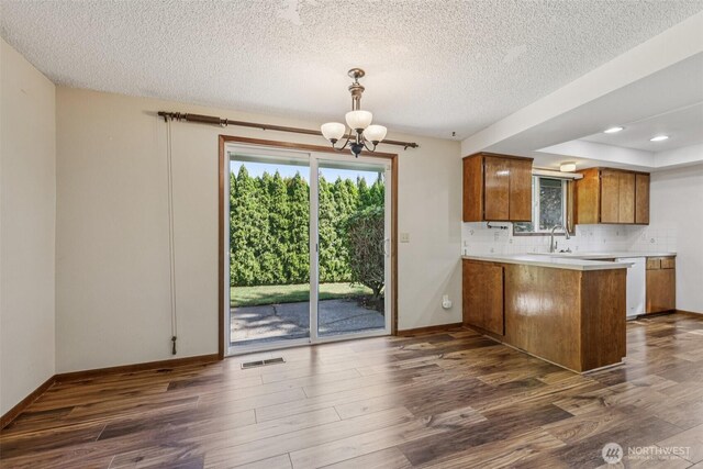 1001 Garden Dr, Lynden, WA 98264 - kitchen featuring brown cabinets, a peninsula, dark wood finished floors, a chandelier, and a textured ceiling