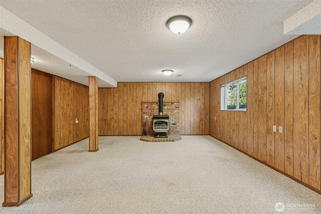 1001 Garden Dr, Lynden, WA 98264 - below grade area with wooden walls, a wood stove, carpet flooring, and a textured ceiling