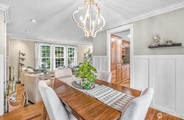 12907 SE 245th St, Kent, WA 98030 - dining space featuring crown molding, a textured ceiling, a chandelier, light wood-style flooring, and a wainscoted wall