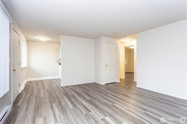 5303 Parker Rd E, Sumner, WA 98390 - unfurnished room with a baseboard radiator, wood finished floors, a textured ceiling, and baseboards