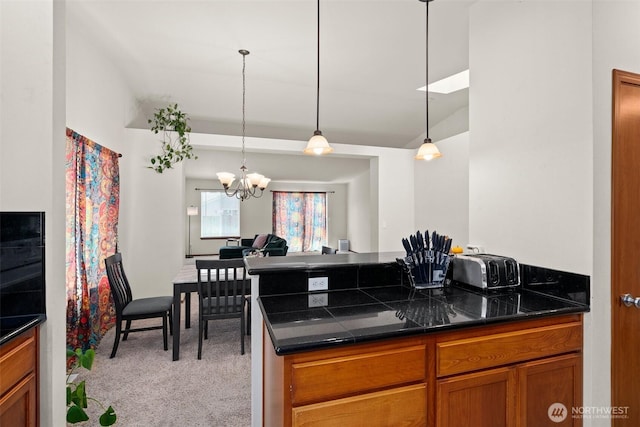 134 Wind River Dr, Chehalis, WA 98532 - kitchen featuring dark countertops, light carpet, a chandelier, brown cabinets, and vaulted ceiling