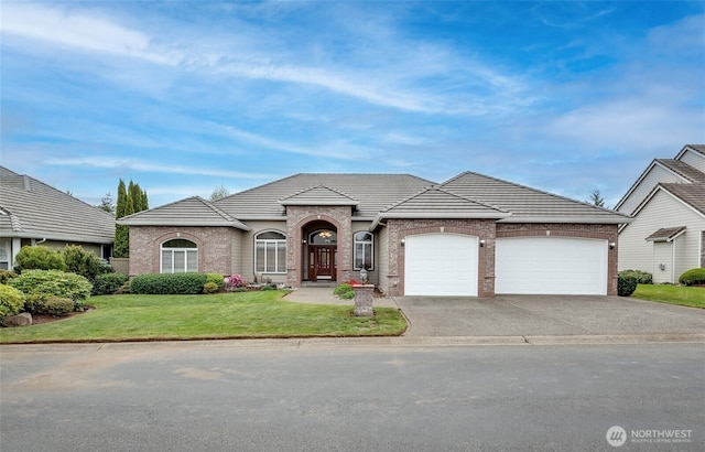 17713 92nd Ave E, Puyallup, WA 98375 - french country home with a garage, driveway, a front yard, brick siding, and a tile roof