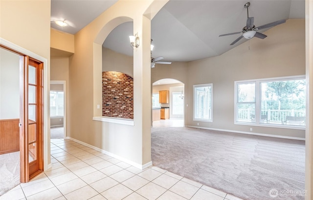 17713 92nd Ave E, Puyallup, WA 98375 - empty room featuring a ceiling fan, light colored carpet, light tile patterned floors, arched walkways, and high vaulted ceiling