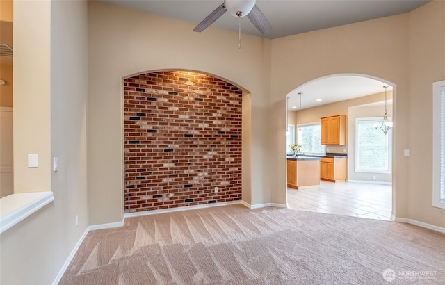 17713 92nd Ave E, Puyallup, WA 98375 - unfurnished living room with light colored carpet, ceiling fan, arched walkways, and brick wall
