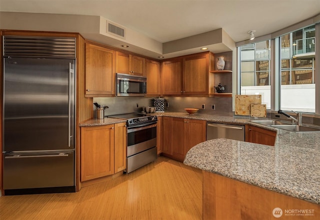 2000 1st Ave Unit 804, Seattle, WA 98121 - kitchen with appliances with stainless steel finishes, brown cabinetry, light wood-style flooring, light stone countertops, and recessed lighting