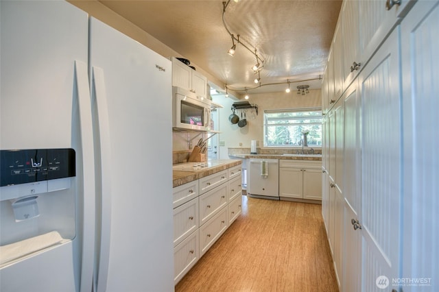 2685 E Hoquiam Rd, Hoquiam, WA 98550 - kitchen with white appliances, white cabinets, light wood finished floors, light countertops, and a sink