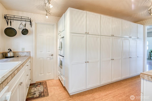 2685 E Hoquiam Rd, Hoquiam, WA 98550 - kitchen with white cabinetry, light countertops, light wood-style floors, and double oven