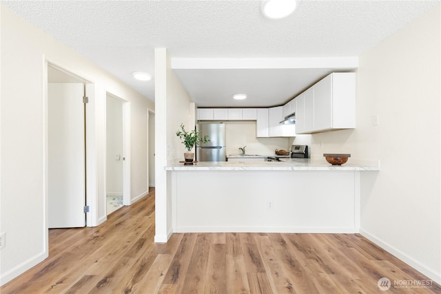 10405 12th Avenue Ct S, Tacoma, WA 98444 - kitchen with appliances with stainless steel finishes, light countertops, light wood finished floors, under cabinet range hood, and white cabinetry
