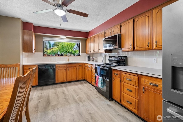 209 Old Hill Rd, Aberdeen, WA 98520 - kitchen featuring black appliances, a textured ceiling, light wood finished floors, light countertops, and brown cabinetry