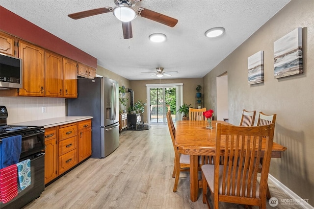 209 Old Hill Rd, Aberdeen, WA 98520 - kitchen featuring appliances with stainless steel finishes, ceiling fan, light wood finished floors, a textured ceiling, and brown cabinetry