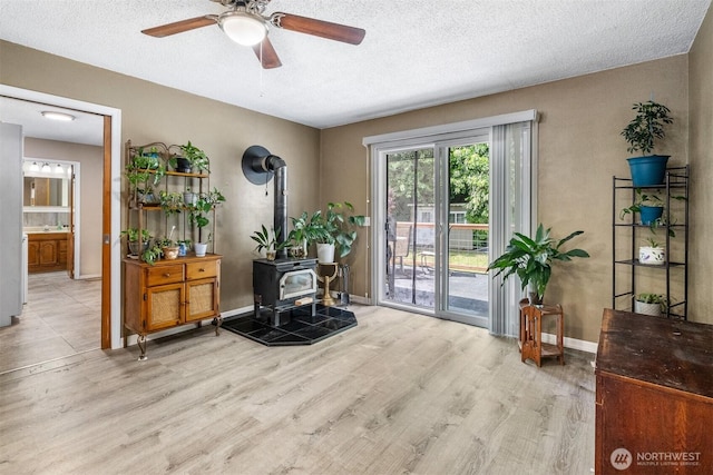 209 Old Hill Rd, Aberdeen, WA 98520 - living area featuring a wood stove, wood finished floors, ceiling fan, and a textured ceiling