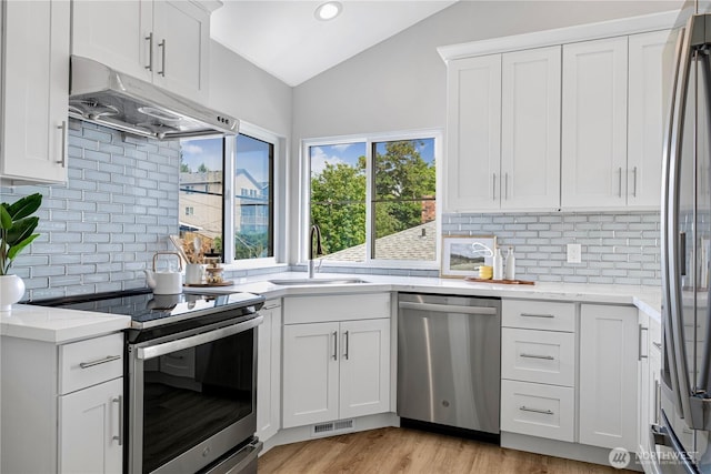 9422 49th Ave S, Seattle, WA 98118 - kitchen featuring stainless steel appliances, under cabinet range hood, lofted ceiling, backsplash, and white cabinets