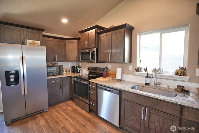 1028 W Sequoia Rd, Moses Lake, WA 98837 - kitchen with appliances with stainless steel finishes, a sink, wood finished floors, light stone countertops, and dark brown cabinetry
