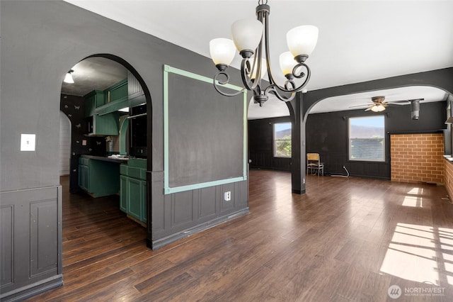 223 Carswell Dr, Moses Lake, WA 98837 - unfurnished dining area with arched walkways, a ceiling fan, dark wood-style flooring, a chandelier, and a wainscoted wall