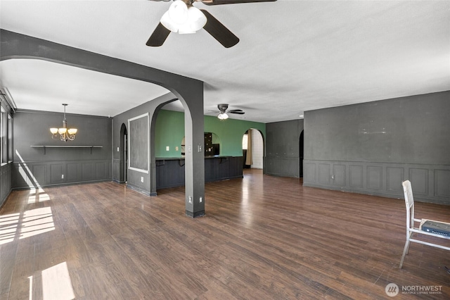223 Carswell Dr, Moses Lake, WA 98837 - unfurnished living room featuring ceiling fan, arched walkways, a decorative wall, a chandelier, and wood finished floors