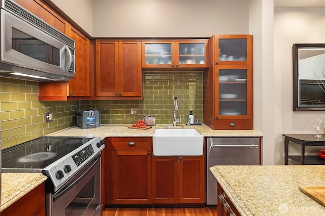 201 Galer St Unit 102, Seattle, WA 98109 - kitchen with appliances with stainless steel finishes, tasteful backsplash, light stone countertops, and glass insert cabinets