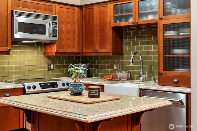 201 Galer St Unit 102, Seattle, WA 98109 - kitchen featuring stainless steel appliances, a breakfast bar area, light stone counters, glass insert cabinets, and tasteful backsplash
