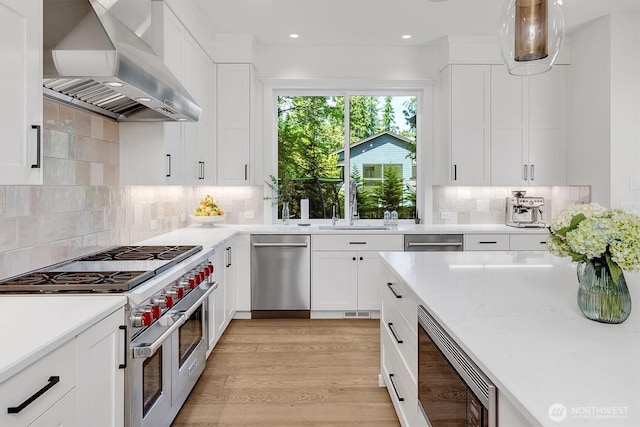 14430 SE 18th St, Bellevue, WA 98007 - kitchen featuring wall chimney range hood, stainless steel appliances, white cabinets, a sink, and light wood-type flooring